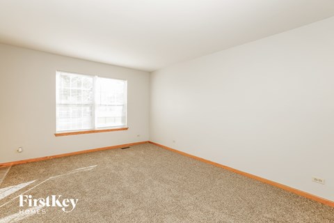 a bedroom with white walls and carpet and a window