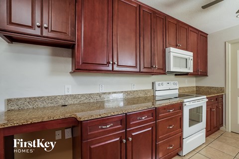 A kitchen with brown cabinets and a FirstKey Homes logo.