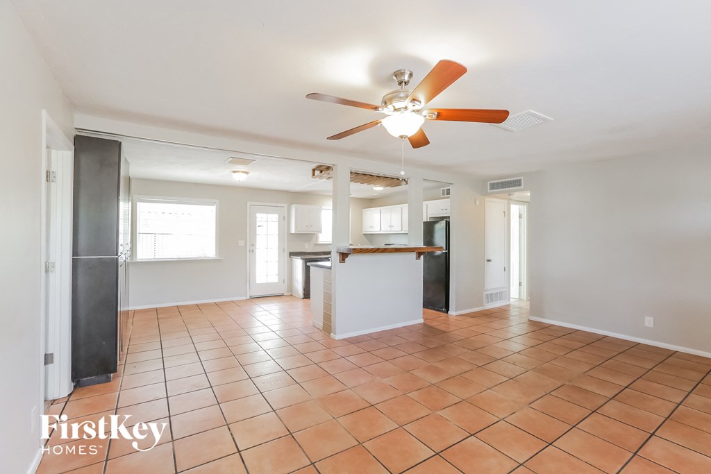 A spacious room with a fan and tile flooring.