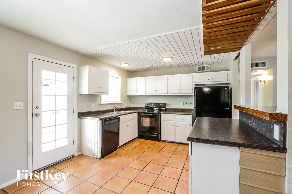 A kitchen with a black counter top and white cabinets.