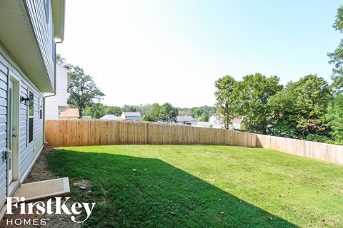 A backyard with a wooden fence and a grassy area.