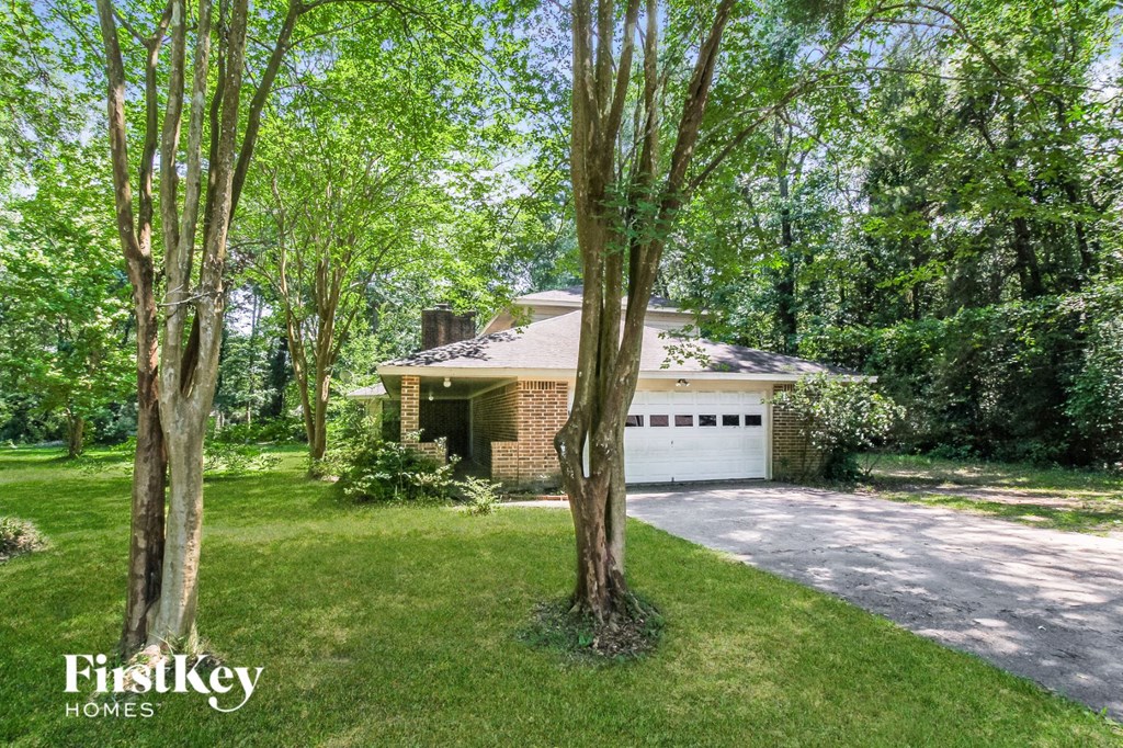 A house with a driveway and trees in front of it.