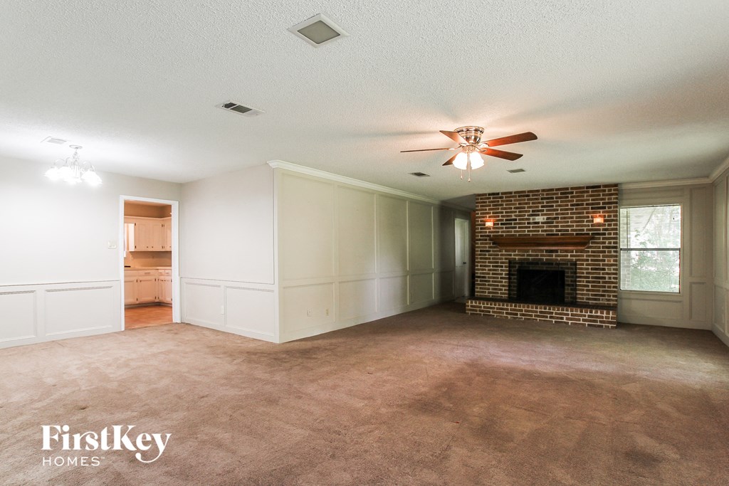 A spacious room with a fireplace and a ceiling fan.
