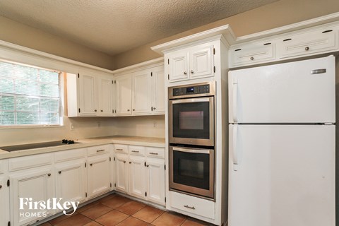 A kitchen with white cabinets and appliances.