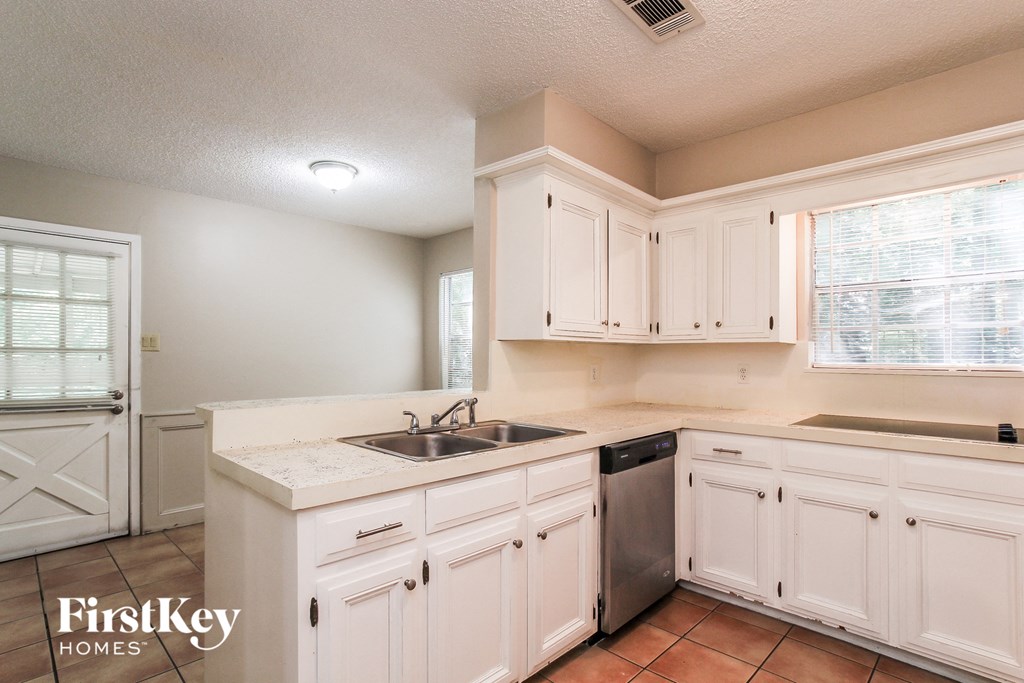 A kitchen with white cabinets and a sink.