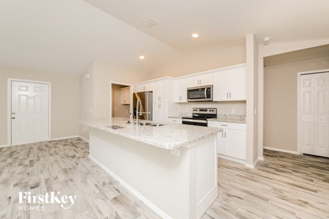 A kitchen with a white island and wooden floors.
