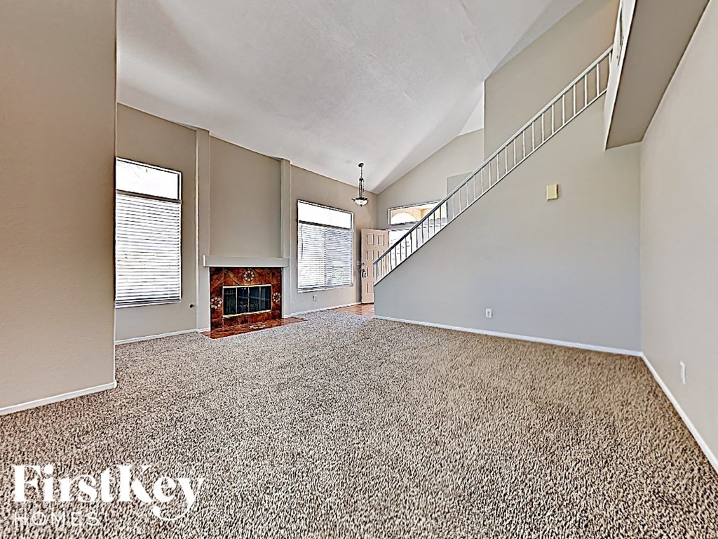 A spacious living room with a fireplace and a staircase.