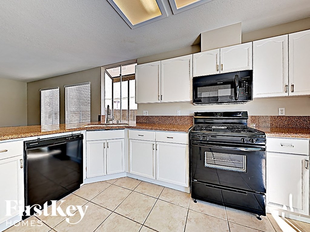 A kitchen with white cabinets and a black stove top oven.
