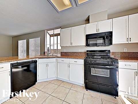 A kitchen with white cabinets and a black stove top oven.