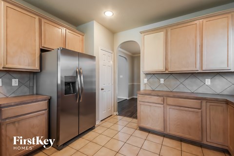 A kitchen with a refrigerator and wooden cabinets.