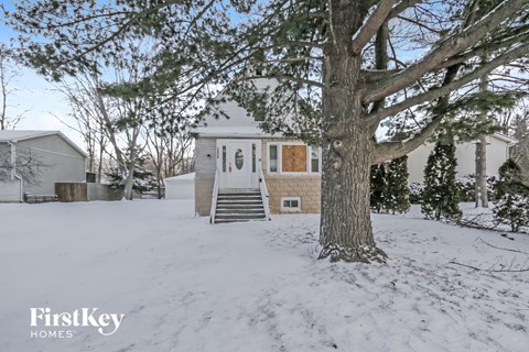 a white house with a large tree in the snow