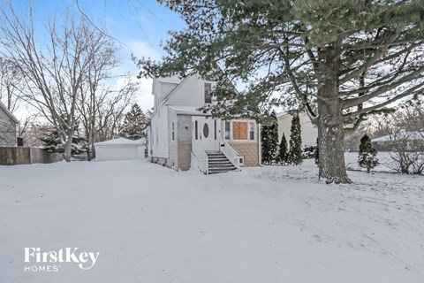 a white house covered in snow with a large tree