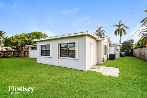 a white house with a lawn and palm trees