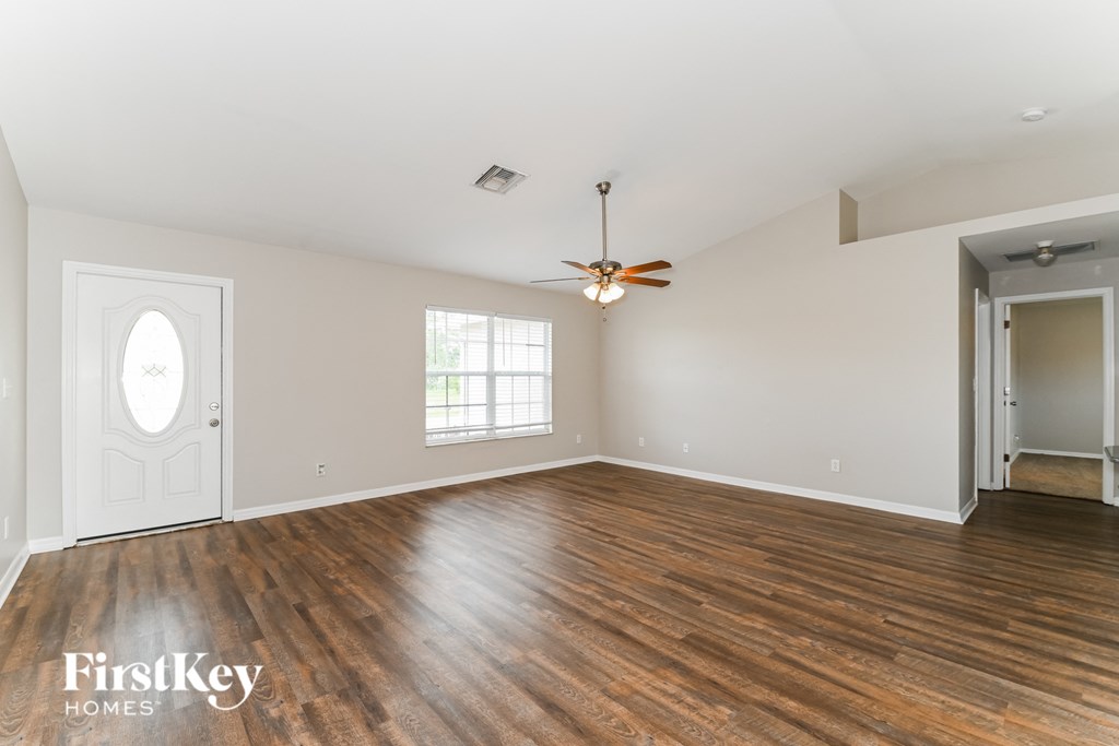 an empty living room with wood floors and a ceiling fan