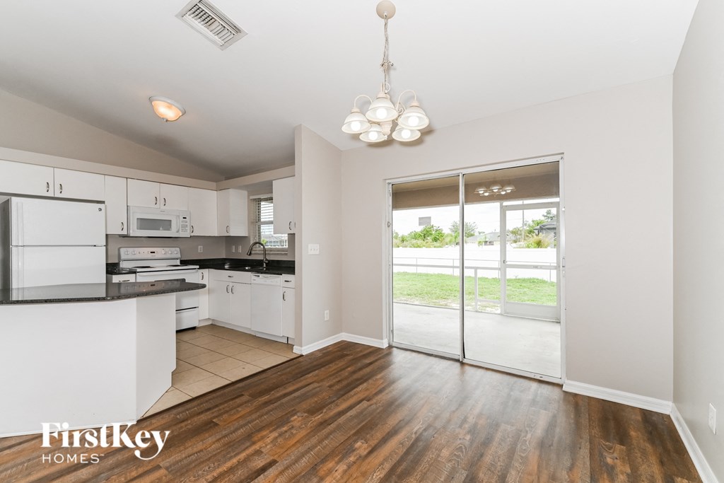 a kitchen with white cabinets and a door to a patio