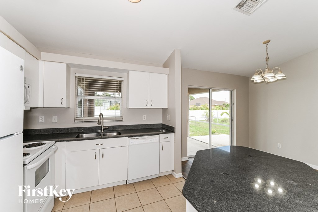 a kitchen with white cabinets and black counter tops
