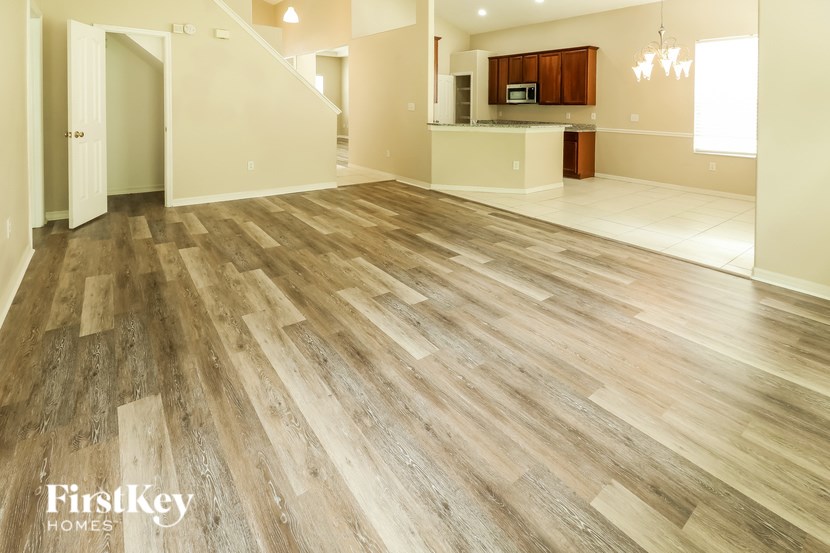 A spacious room with wooden flooring and a staircase leading to another room.