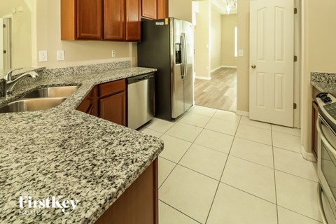 A kitchen with granite countertops and a stainless steel refrigerator.