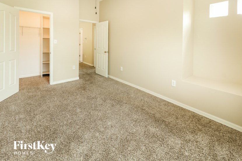 A carpeted room with two doors and a window.