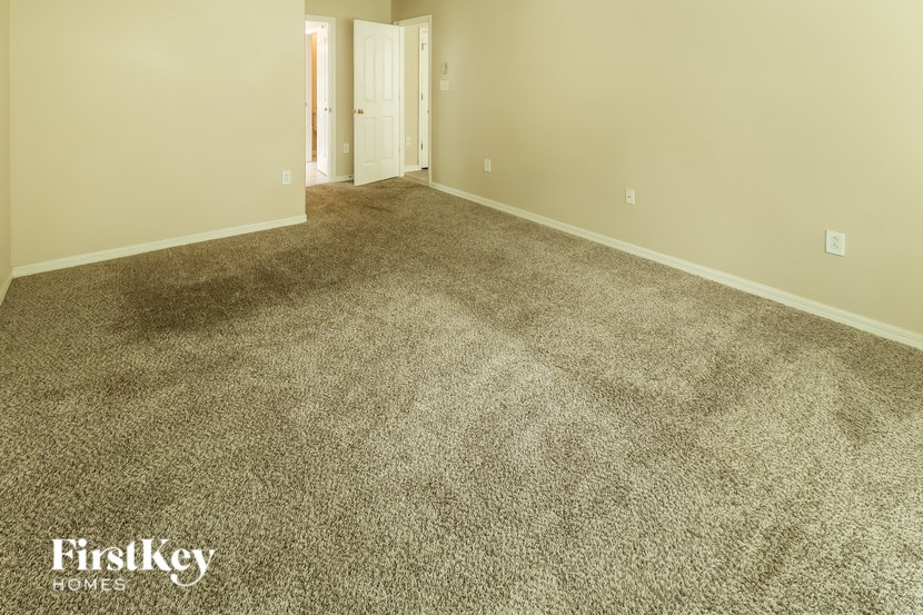 A carpeted room with a doorway leading to another room.