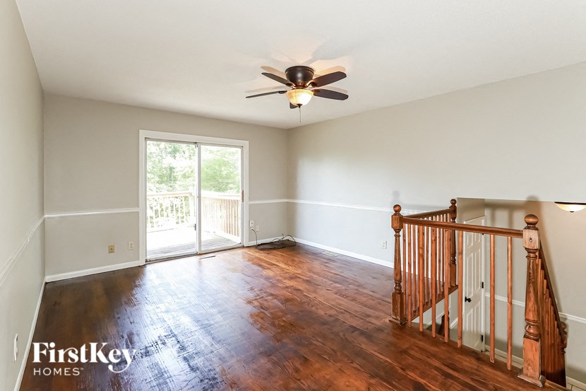 an empty living room with a ceiling fan and wood floors
