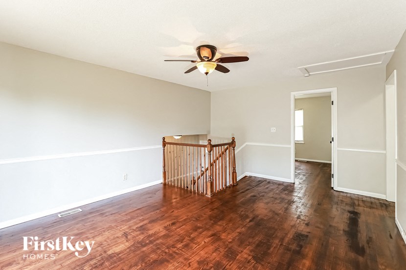an empty living room with wood flooring and a ceiling fan