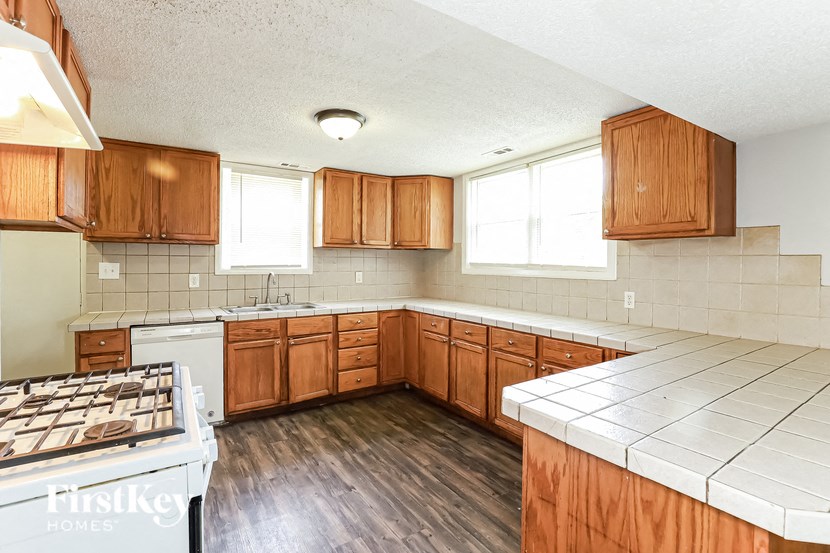 an empty kitchen with wooden cabinets and white appliances
