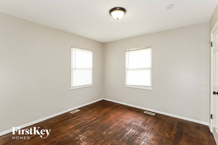 a empty room with a wood floor and two windows
