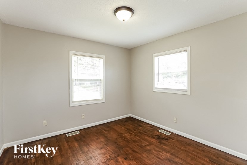 an empty room with a hardwood floor and two windows