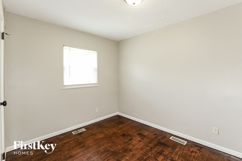 an empty room with wood flooring and a window