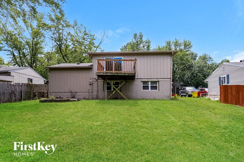a backyard with a house with a deck on top of it