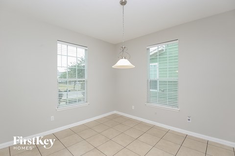 an empty dining room with a pendant light and tiled floor