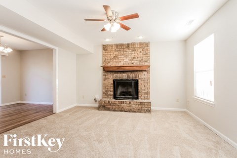 a living room with a brick fireplace and a ceiling fan