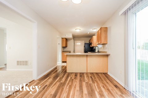 the living room and kitchen of an apartment with wood flooring and a large window