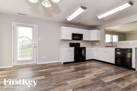A kitchen with wooden floors and white cabinets.