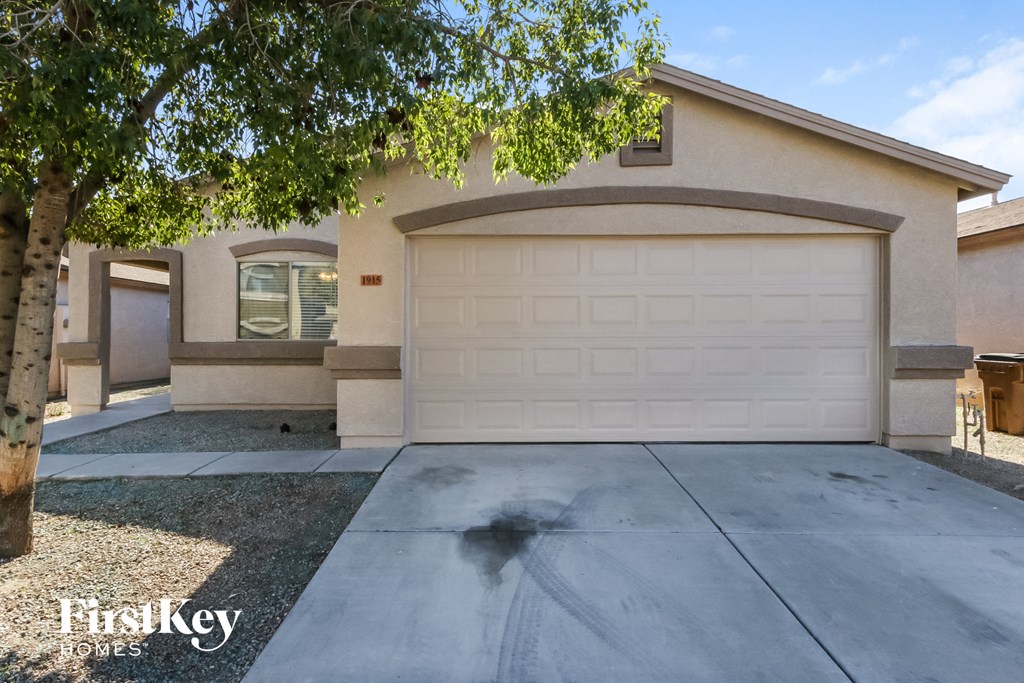 A house with a garage door and a tree in front.