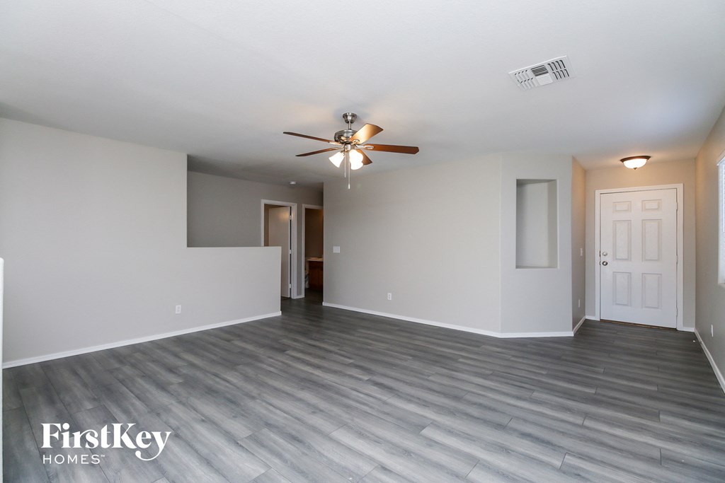 A spacious room with a ceiling fan and lighting fixture.