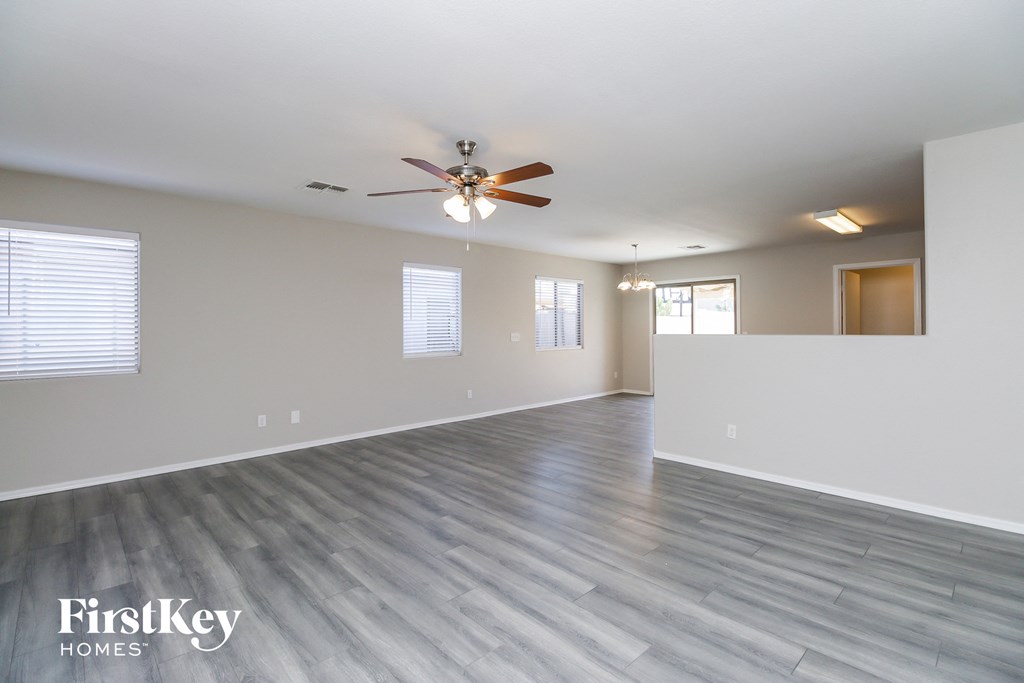 A spacious room with a ceiling fan and lighting fixture.
