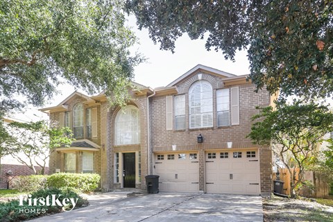A house with a garage is surrounded by trees.