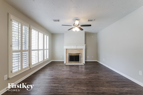 A spacious room with a fireplace and a ceiling fan.