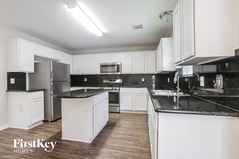A kitchen with black countertops and white cabinets.