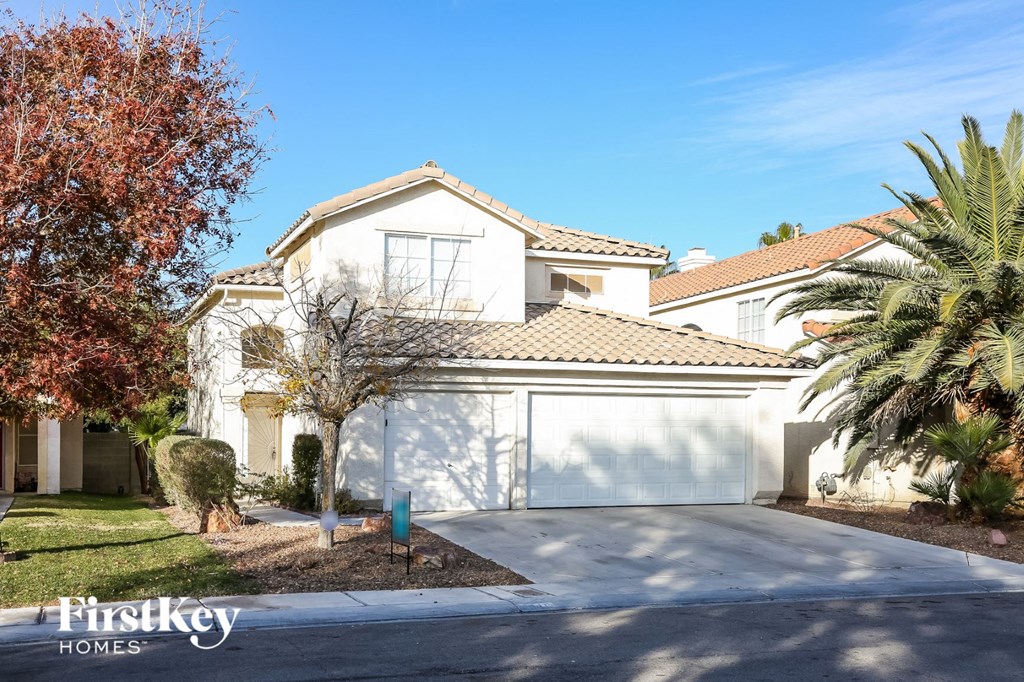 a white house with a garage door and a palm tree