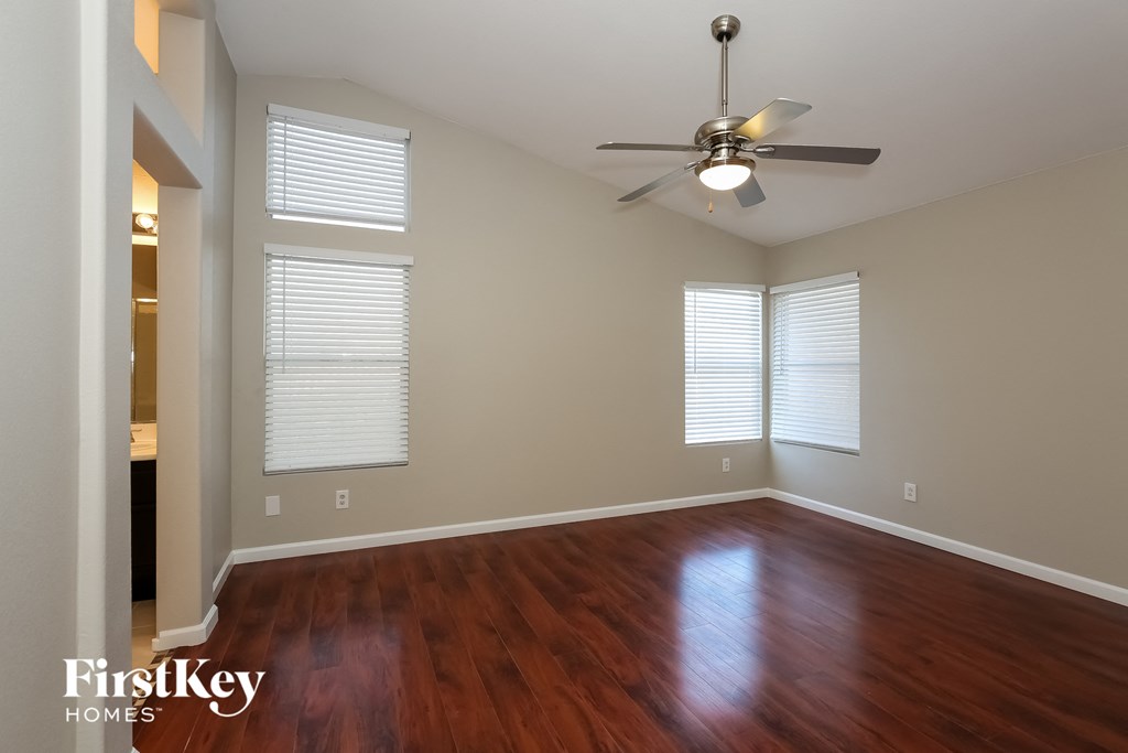 an empty living room with wood floors and a ceiling fan