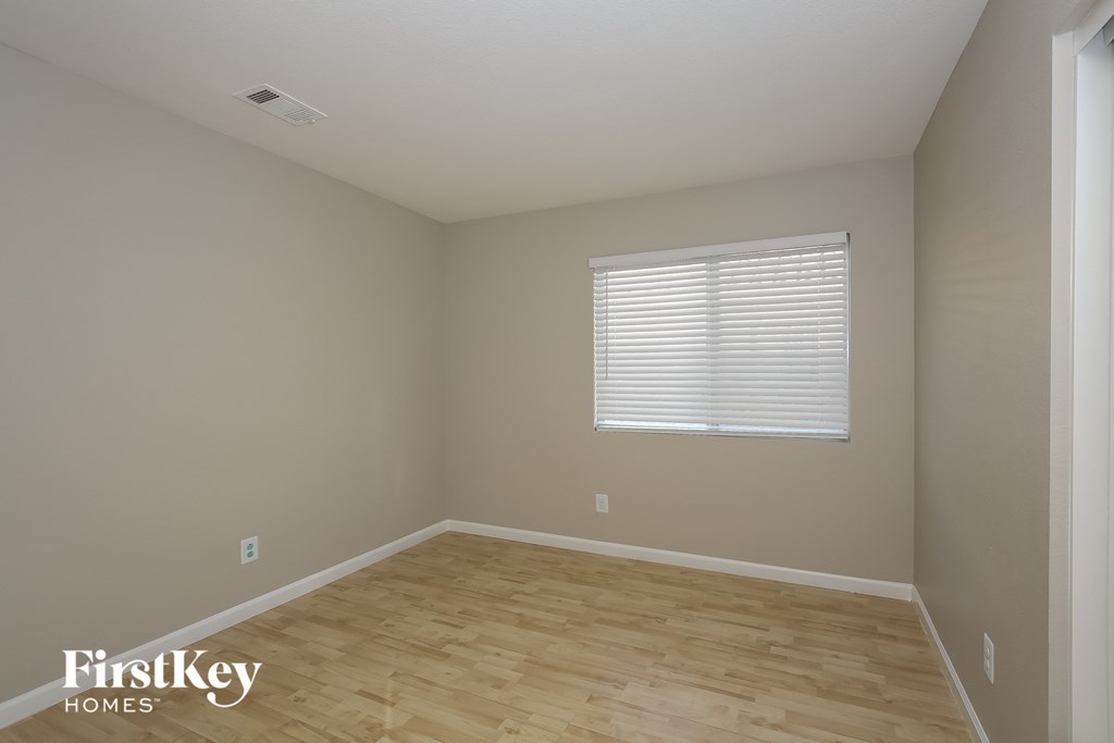 the second bedroom with wood floors and a window