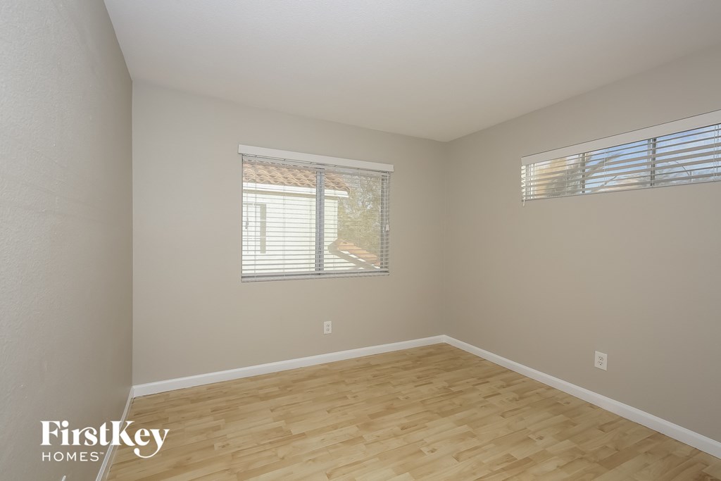 a spacious living room with wood flooring and two windows