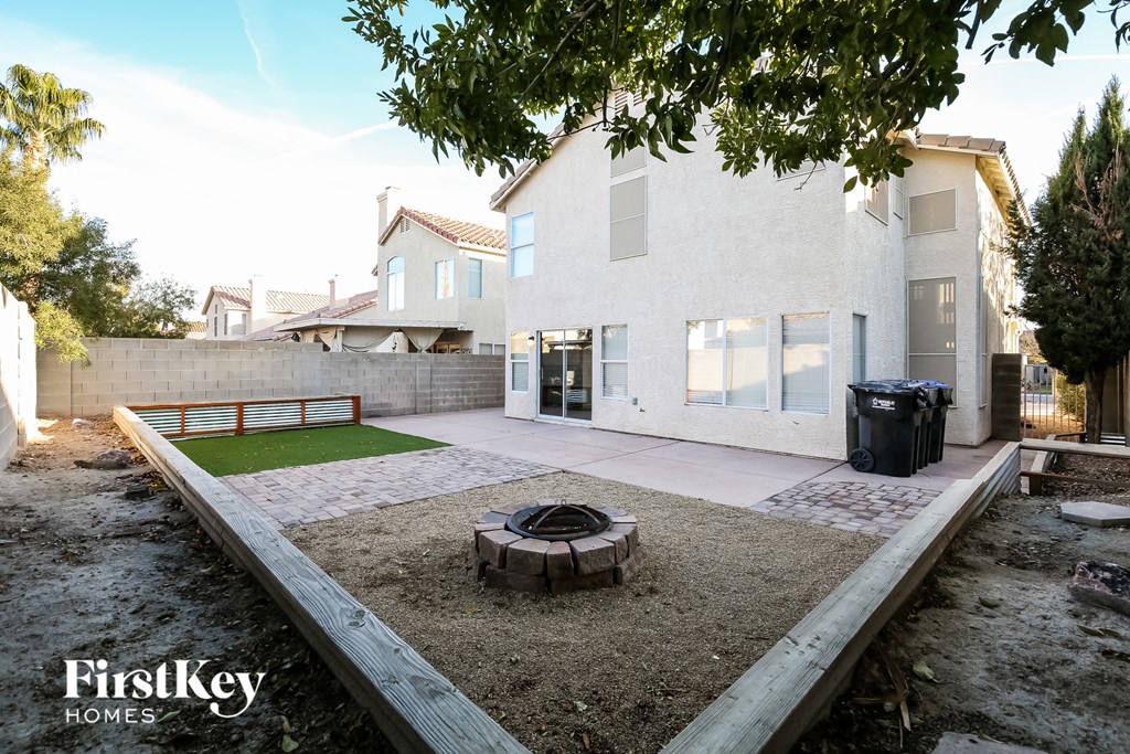 a backyard with a fire pit and a white house