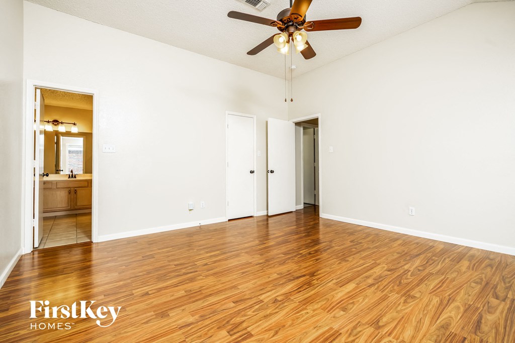 an empty living room with wood floors and a ceiling fan