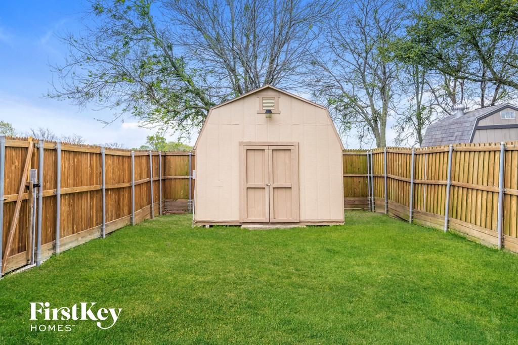 a backyard with a wooden fence and a shed with a door