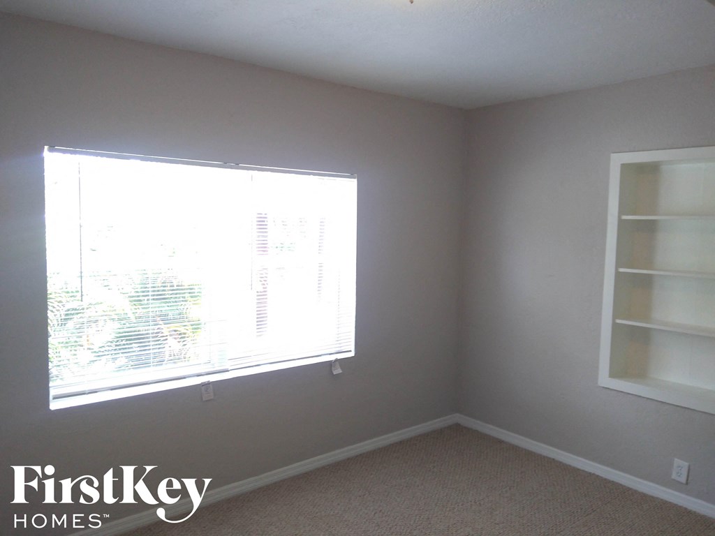 A room with a window and a carpeted floor.