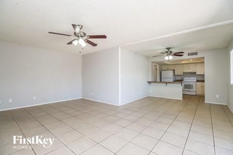 A spacious room with a ceiling fan and a kitchenette in the background.